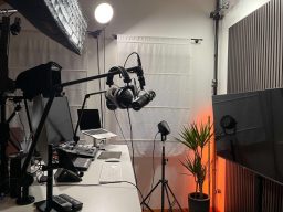 Raum mit Mikrofonen, Monitoren, Pflanzen und einer warmen Beleuchtung.