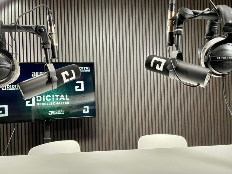 Mikrofone und Kopfhörer im Studio vor einem Bildschirm mit "Digital"-Text.
