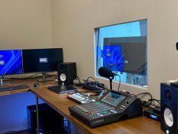 Moderne Audio- und Videoproduktionseinrichtung mit Monitoren und Mischpult.